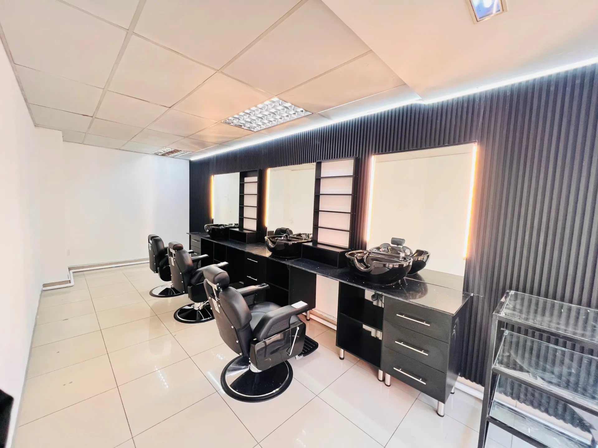 Inside Velvet Edge — black barber chairs, wash basins and illuminated mirror stations at Wierda Mall, Centurion
